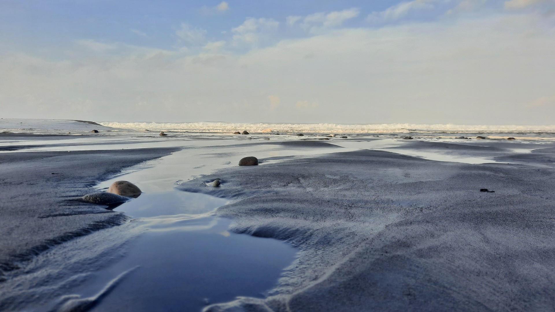 Keindahan Pantai Bambang di Pasirian, Lumajang, memikat wisatawan lewat hamparan pasir hitam eksotis dan bebatuan estetik yang cocok dijadikan spot foto.
